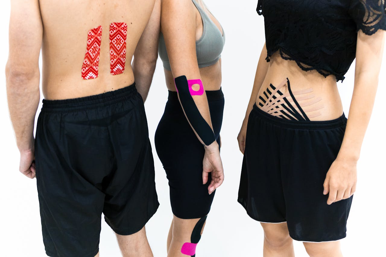 Adults with kinesiology tape applied on back, abdomen, and arm for therapeutic support.